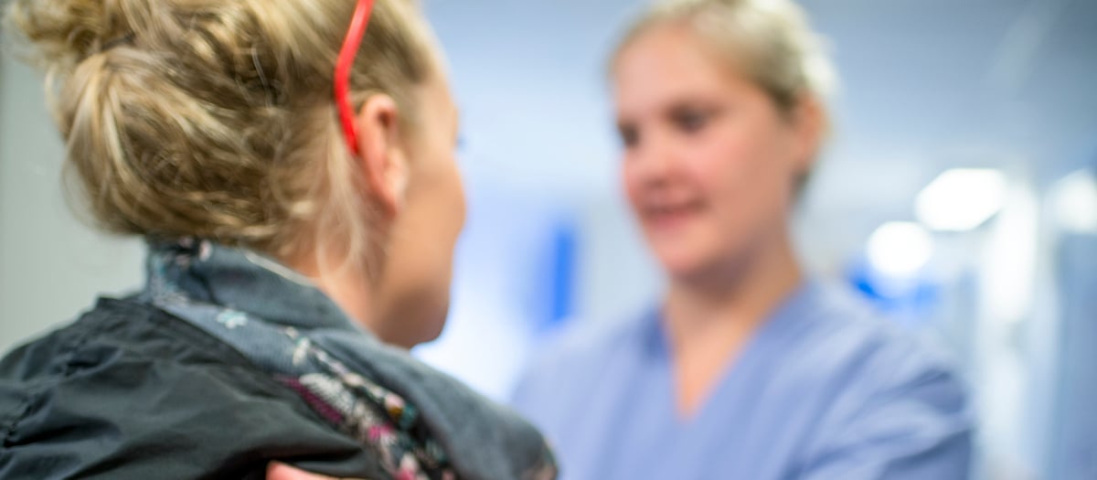 Sjukvårdspersonal som har handen på en patients axel